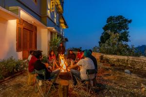 a group of people sitting around a fire at The Hosteller Mussoorie, Mall Road in Mussoorie