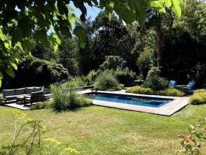 a swimming pool in a garden with two lounge chairs at Landhuis het Woud. max. 11 pers. with private pool in Bergen