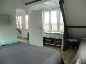 a bedroom with a bed and two windows in a room at Landhuis het Woud. max. 11 pers. with private pool in Bergen