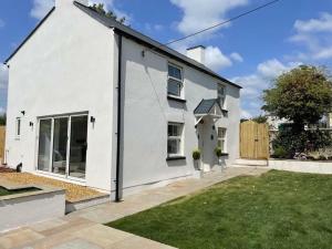 a white house with a lawn in front of it at Charming Cottage close to M4 Bridgend in Bridgend