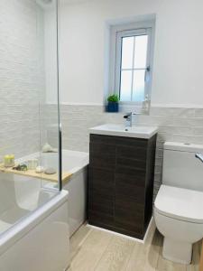 a white bathroom with a toilet and a sink at Charming Cottage close to M4 Bridgend in Bridgend