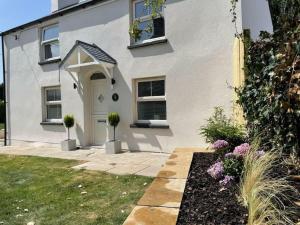 a white house with a white door and some flowers at Charming Cottage close to M4 Bridgend in Bridgend