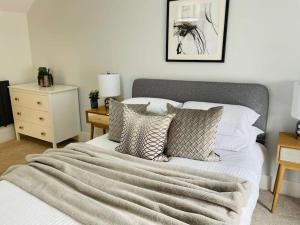 1 dormitorio con 1 cama con manta y almohadas en Charming Cottage close to M4 Bridgend, en Bridgend