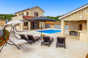 a patio with chairs and an umbrella and a pool at Villa Giulietta in Vrbnik