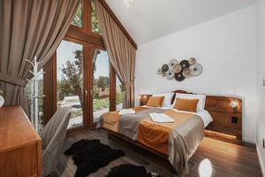 a bedroom with a bed and a large window at Toplik Village Resort in Uzdojnice