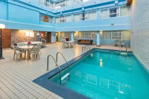 a pool in a hotel with a table and chairs at Comfort Inn & Suites in Edmonton