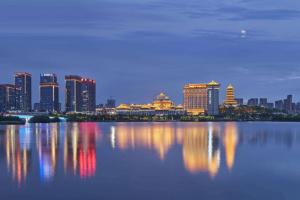 een skyline van de stad 's nachts met een grote hoeveelheid water bij Howard Johnson by Wyndham Jimei Lake Plaza Xiamen in Xiamen