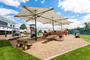 einen Park mit Spielplatz mit Sonnenschirm und Bänken in der Unterkunft Daisy's luxury caravan at tattershall lakes in Lincoln
