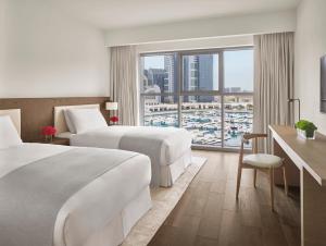 a hotel room with two beds and a large window at The Abu Dhabi EDITION in Abu Dhabi