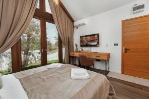a bedroom with a bed and a desk and a window at Toplik Village Resort in Lukavica