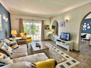 a living room with a couch and a tv at Casa Buccaneer, 2 Bedroom Garden Apartment in Praia da Luz in Luz