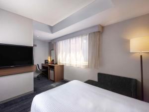 京都市にあるイビススタイルズ京都四条のベッド1台、薄型テレビが備わるホテルルームです。