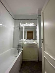 La salle de bains est pourvue d'un lavabo, d'une baignoire et d'un miroir. dans l'établissement Casa Buccaneer, 2 Bedroom Garden Apartment in Praia da Luz, à Luz