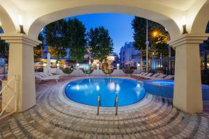 - une piscine avec une arche dans une ville la nuit dans l'établissement Parco dei Principi Boutique Hotel, à Rimini