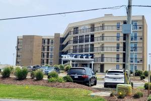 a parking lot with cars parked in front of a building at Ocean Reef Suites in Kill Devil Hills