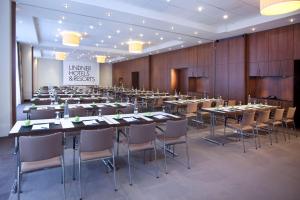 a conference room with tables and chairs and a screen at Lindner Hotel Hamburg am Michel, part of JdV by Hyatt in Hamburg