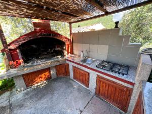 an outdoor kitchen with a stove and a fireplace at Robinson Ina 1 in Gdinj