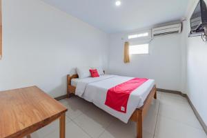a small bedroom with a bed and a table at RedDoorz Syariah at Pantai Pelabuhan Ratu in Sukabumi