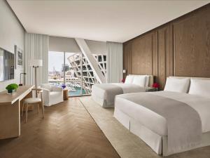 um quarto de hotel com duas camas e uma secretária e uma secretária em The Abu Dhabi EDITION em Abu Dhabi