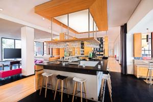 a large kitchen with a bar with stools at Lindner Hotel Frankfurt Sportpark, part of JdV by Hyatt in Frankfurt/Main