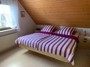 a bedroom with a bed with striped sheets and a window at Gisela Hollmann in Groß Wittensee