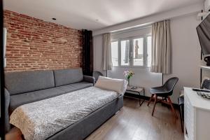 - un salon avec un canapé et un mur en briques dans l'établissement Ático Centro de Madrid, à Madrid