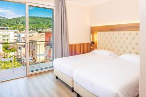 a hotel room with two beds and a large window at Hotel Centrale in Garda