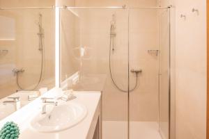 a white bathroom with a sink and a shower at Hotel Centrale in Garda