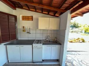 uma cozinha branca com um fogão e um lavatório em Robinson Ina 2 em Selca kod Bogomolja