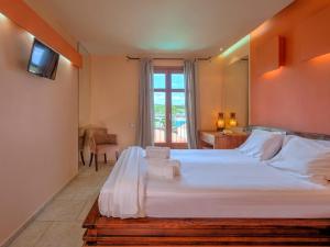a bedroom with a large white bed and a window at Fiscardo Bay Hotel in Fiskardo