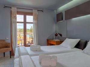 a hotel room with two beds and a window at Fiscardo Bay Hotel in Fiskardo
