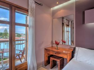 a bedroom with a bed and a desk and a balcony at Fiscardo Bay Hotel in Fiskardo