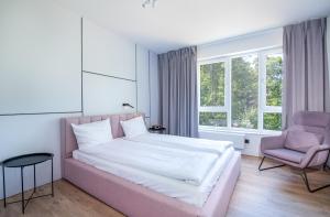 波皮耶洛伯的住宿－Apartamenty na Wydmach，一间卧室配有一张大床和一张粉红色的椅子