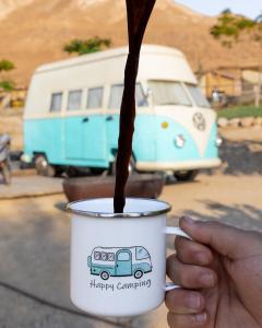 a person holding a coffee cup with a drink at Ein Gedi Camp Lodge in Ein Gedi
