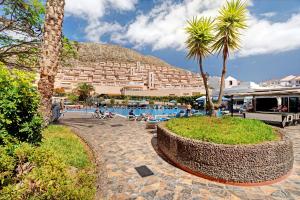 a resort with a pool and palm trees and a building at El Palomar de Atteserg in Los Cristianos