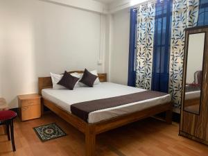 a bedroom with a bed with blue curtains and a mirror at Aama Home Stay in Kurseong