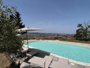 a swimming pool with two chairs and an umbrella at Antica Colombaia in Volterra
