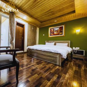 Schlafzimmer mit einem Bett, grünen Wänden und Holzböden in der Unterkunft Safina Hotel Skardu in Skardu