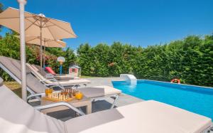 a villa with a swimming pool and a patio with chairs and an umbrella at Villa Andreas A Private Paradise in Mouzákion