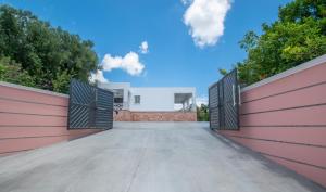 a driveway with a pink fence and gates at Villa Andreas A Private Paradise in Mouzákion
