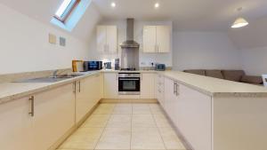 a large kitchen with white cabinets and a sink at Carriage Crescent in Witney