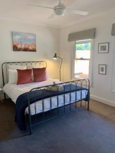 a bedroom with a bed with red pillows and a window at The Birches Beechworth in Beechworth
