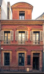 a red brick building with windows on a street at La maison du tripot in Honfleur