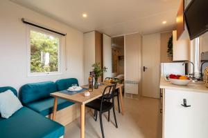 kuchnia i salon ze stołem i niebieską kanapą w obiekcie L'Olivier mobil-home climatisé avec une vue mer exceptionnelle w Hyères +7 zdjęć