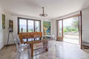 a dining room with a glass table and chairs at Calenzana Cinque - Appt avec piscine partagée in Calvi