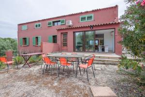 a table and chairs in front of a pink house at Calenzana Cinque - Appt avec piscine partagée in Calvi