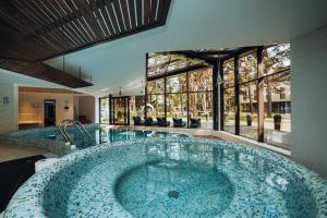 a large swimming pool with a large tub in a house at Gabija Hotel SPA & Conferences in Palanga