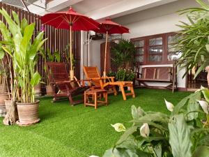 a patio with grass and chairs and umbrellas at Apilapa House in Chiang Mai