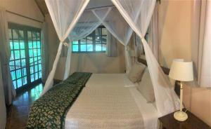 a bedroom with a canopy bed and a window at Family Lodge in Natural African Bush - 2115 in Bulawayo +18 photos