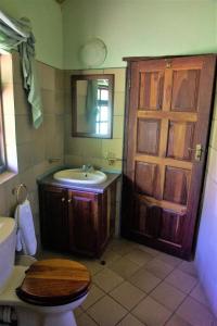 a bathroom with a toilet and a sink and a door at Family Lodge in Natural African Bush - 2115 in Bulawayo